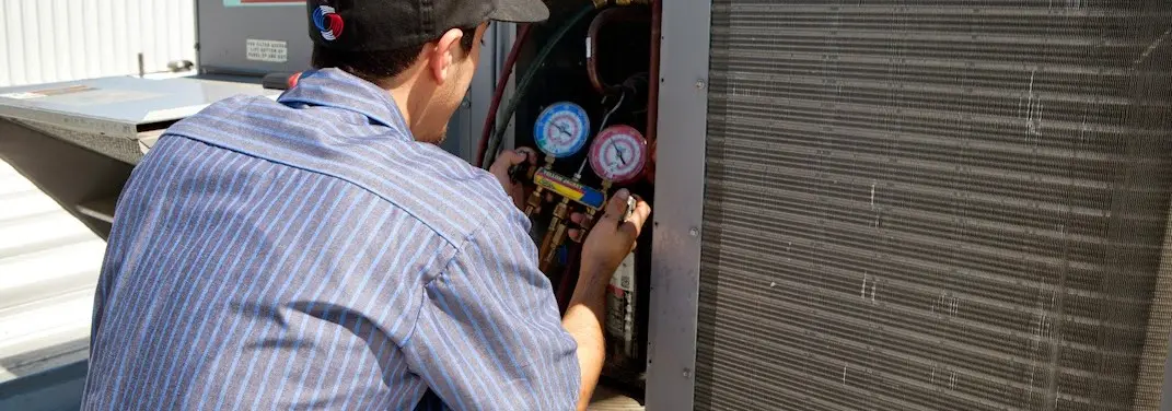 HVAC technician servicing a condenser unit in Watford City